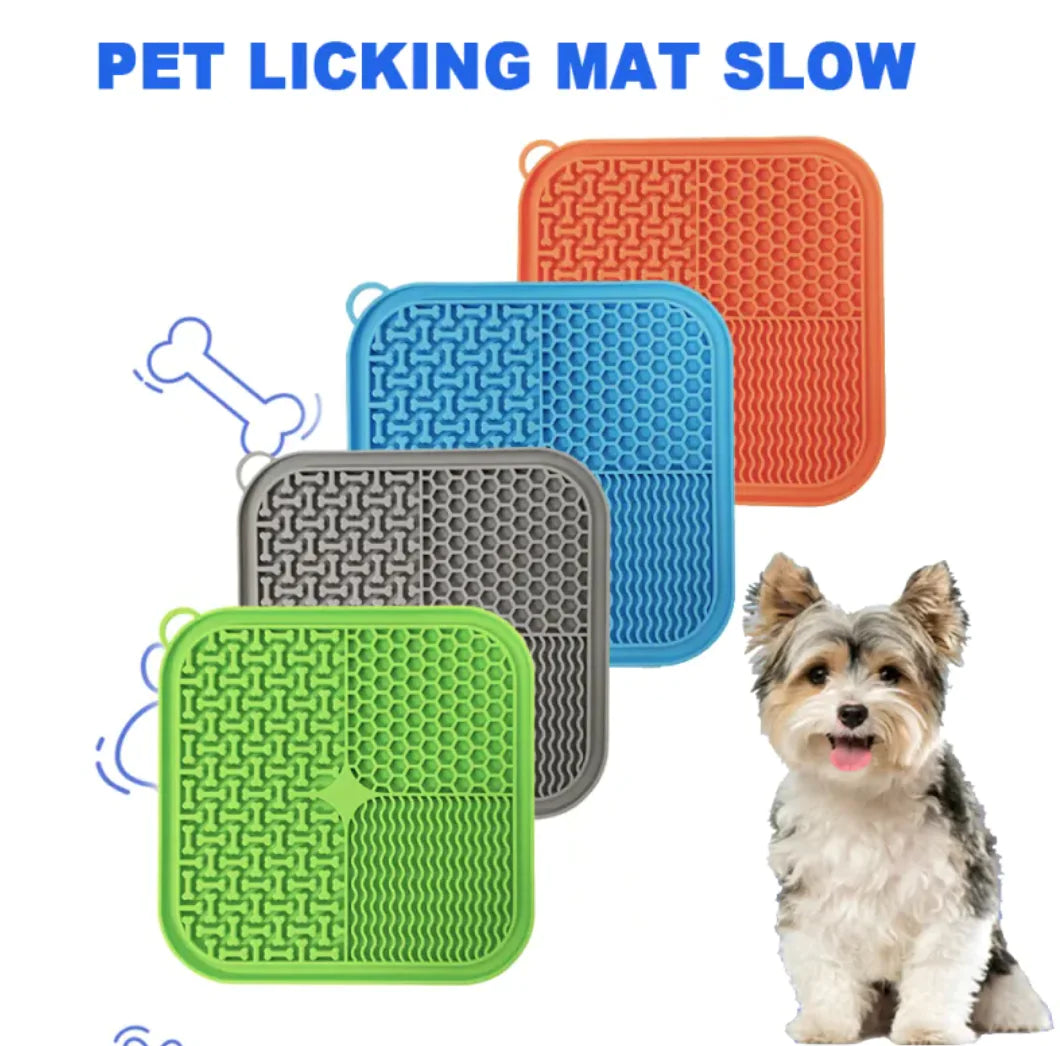 Four pet licking mats in different colors with a dog sitting next to them.
