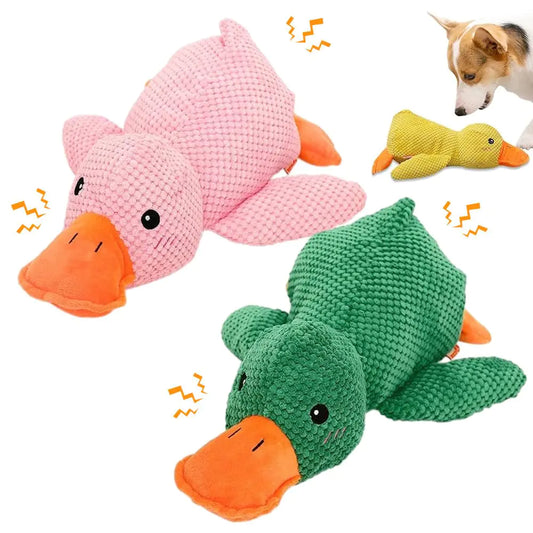 Two knitted duck toys, one pink and one green, with a dog playing with a yellow toy in the background.