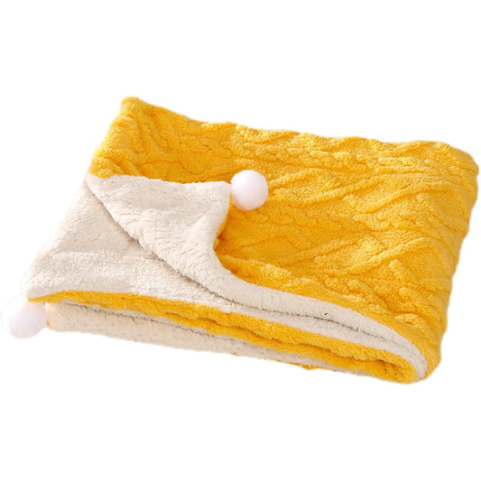 Yellow and white textured blanket with pom-poms on a white background